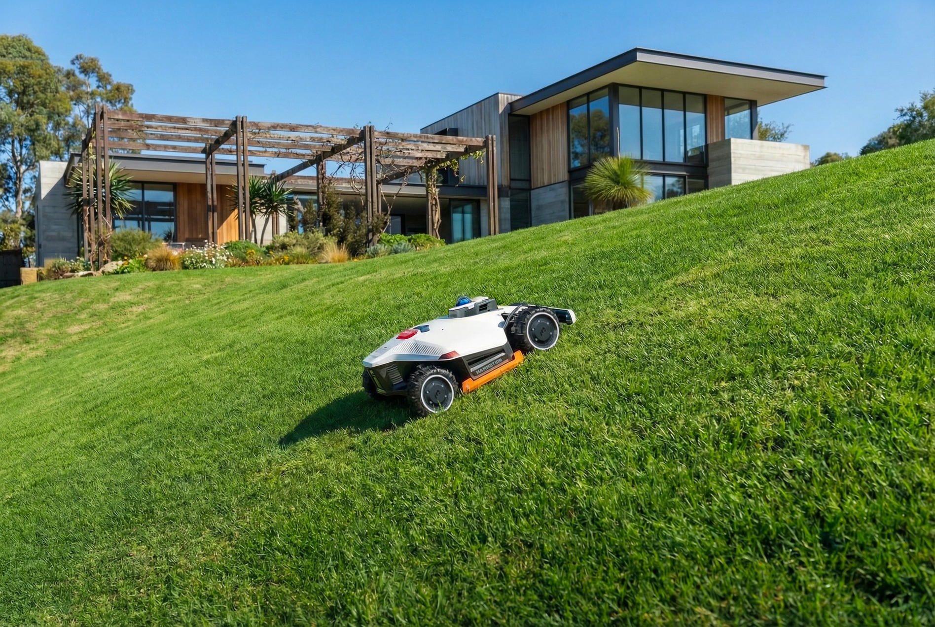 Robotic mower climbing a slope beside a modern house